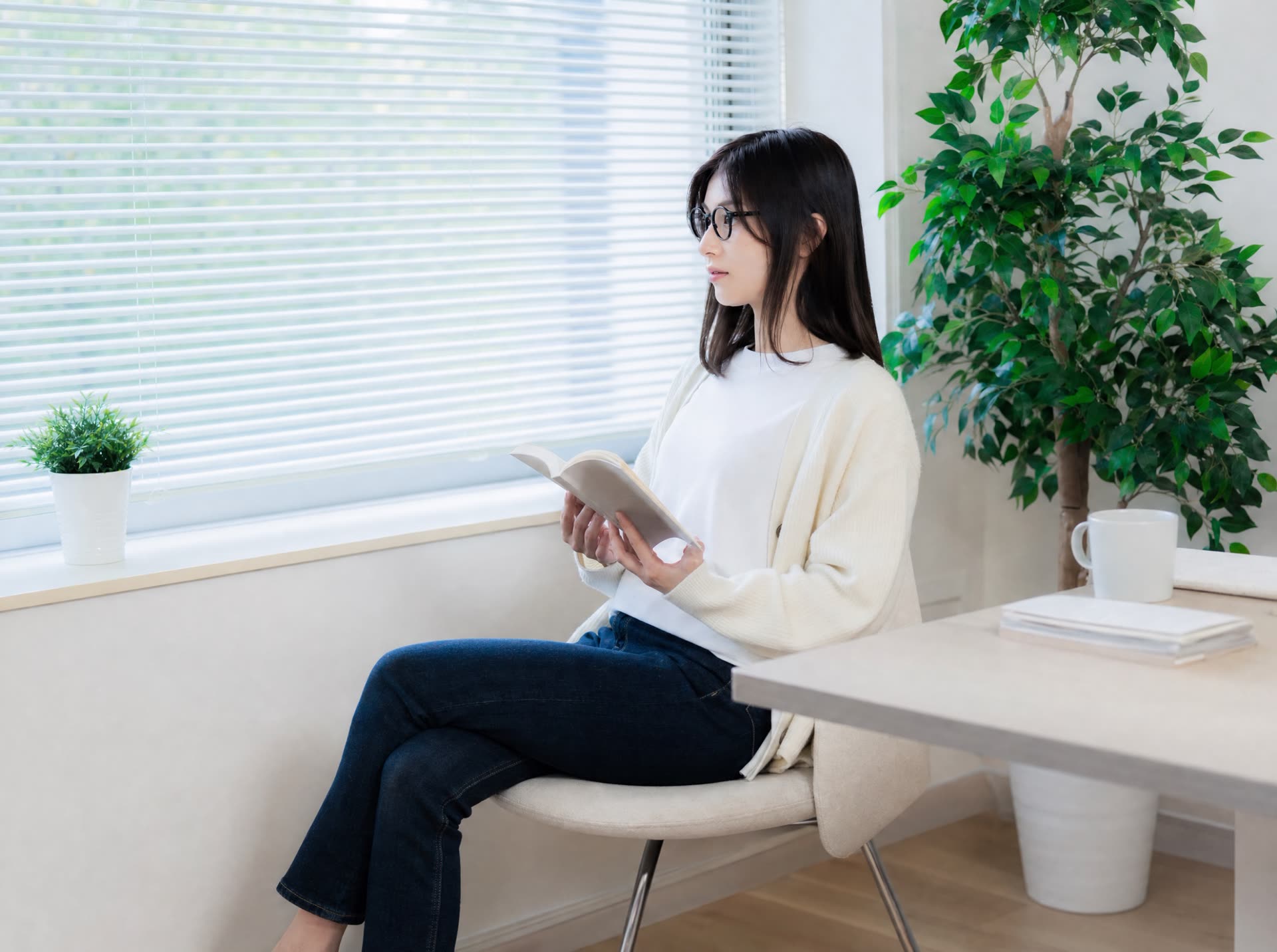 窓辺で読書を楽しむメガネの女性